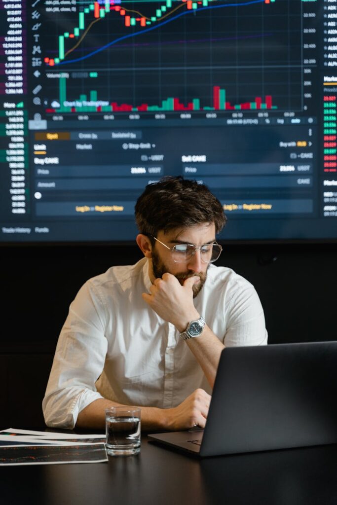 bearded man in white dress shirt wearing eyeglasses sitting in front of laptop feeling pensive